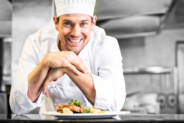 Chef masculin souriant avec des plats cuisinés dans la cuisine