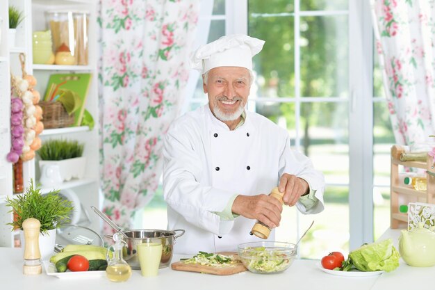 Chef masculin supérieur préparant le dîner dans la cuisine