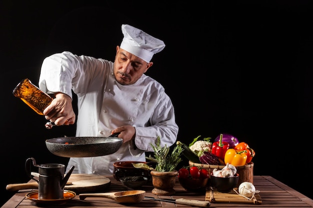 Chef masculin en uniforme blanc versant du vinaigre sur la casserole