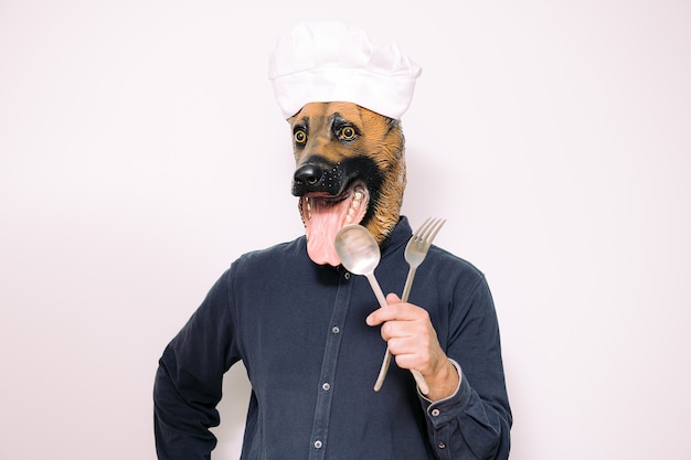 Chef avec masque de chien montrant des ustensiles de cuisine