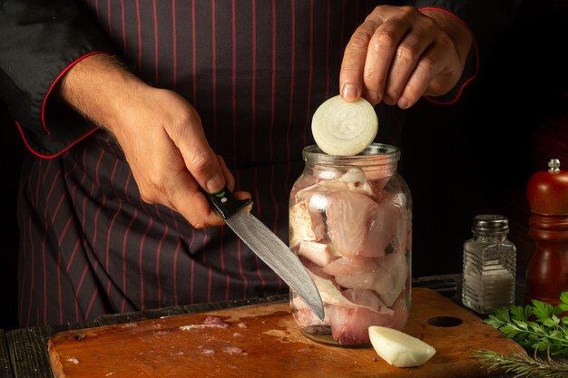 Le chef met des oignons hachés dans un pot de poisson cru Concept de saler ou de conserver du poisson à la maison avec des épices et de la coriandre