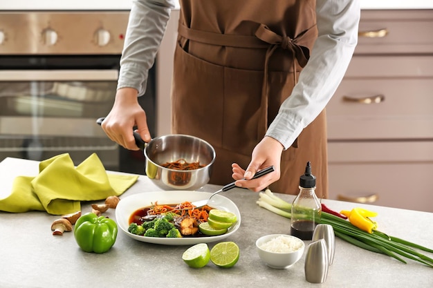 Chef mettant la carotte en sauce sur une assiette avec du poisson au restaurant