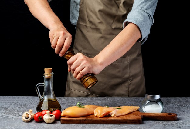 Le chef moud du poivre pour faire mariner la poitrine de poulet