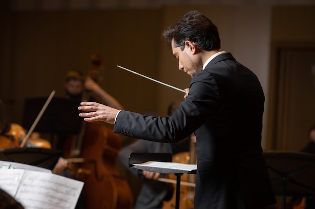 Photo chef d'orchestre symphonique avec interprètes sur fond de salle de concert
