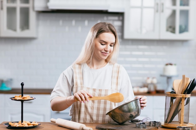 Chef pâtissier confiseur jeune femme de race blanche avec un bol de cuisine sur la table de la cuisine