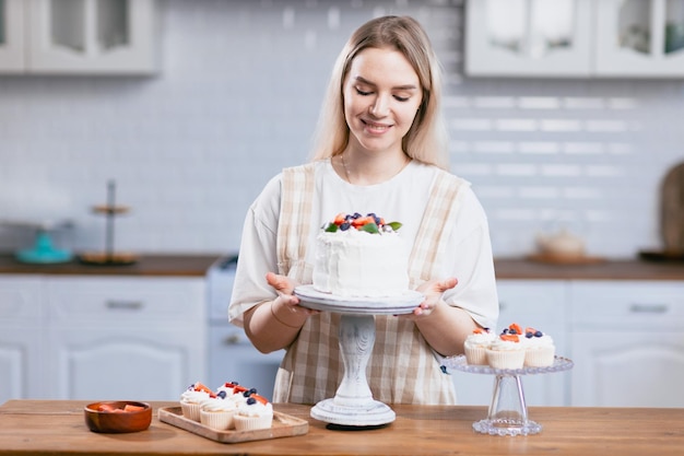 Chef pâtissier confiseur jeune femme de race blanche avec un gâteau sur la table de la cuisine