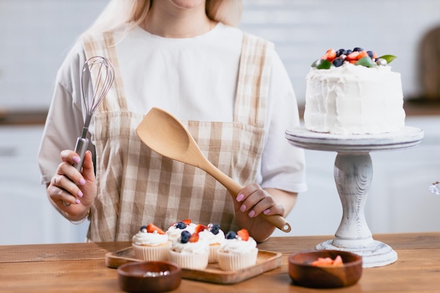 Chef pâtissier confiseur jeune femme de race blanche avec un gâteau sur la table de la cuisine