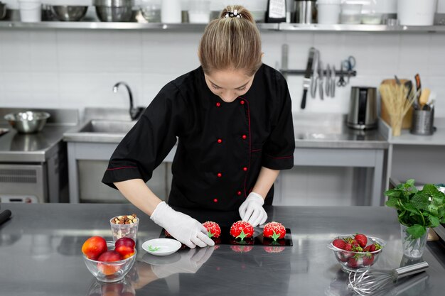 Le chef pâtissier décore le gâteau mousse rouge comme une fraise.