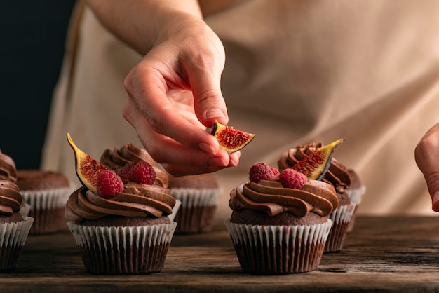 Chef pâtissier décore des muffins aux framboises et aux figues Close up of cupcakes préparation