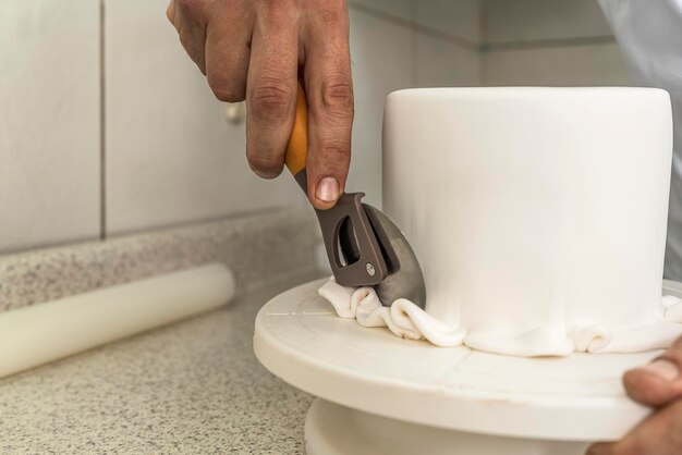 Chef pâtissier enlevant l'excédent d'un gâteau dans une cuisine