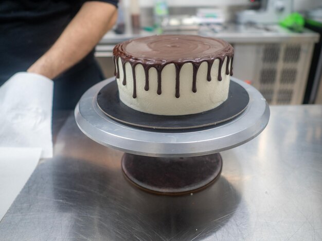 Chef pâtissier gâteau décoration designer un glaçage au chocolat noir givré gâteau blanc avec brown dégoulinant de garniture de ganache
