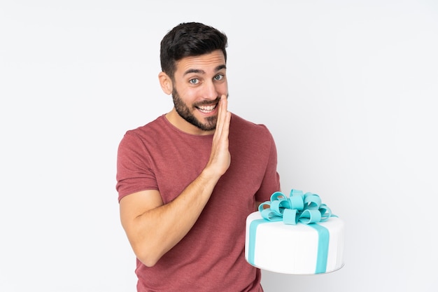 Chef pâtissier avec un gros gâteau isolé sur mur blanc chuchoter quelque chose