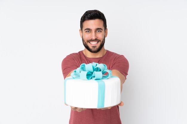 Chef pâtissier avec un gros gâteau sur mur blanc