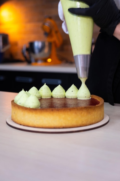 Photo le chef pâtissier presse la crème verte fouettée sur un sablé à la pistache
