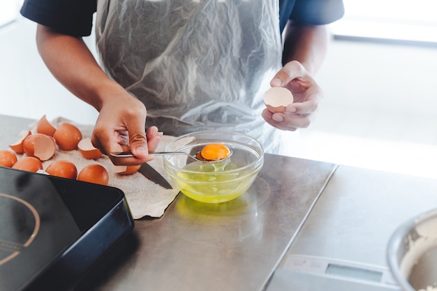 Le chef pâtissier a séparé le jaune de l&#39;œuf blanc dans un bol en verre pour la cuisson du gâteau.