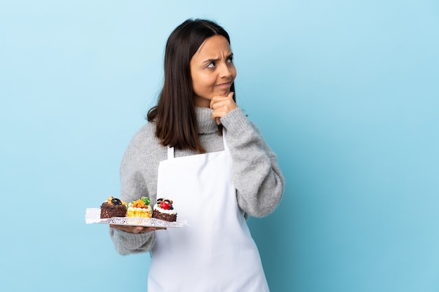 Chef pâtissier tenant un gros gâteau isolé