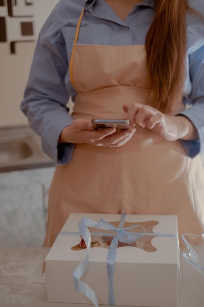 Photo une chef pâtissière prend des photos sur son téléphone portable pour faire la publicité de son entreprise.