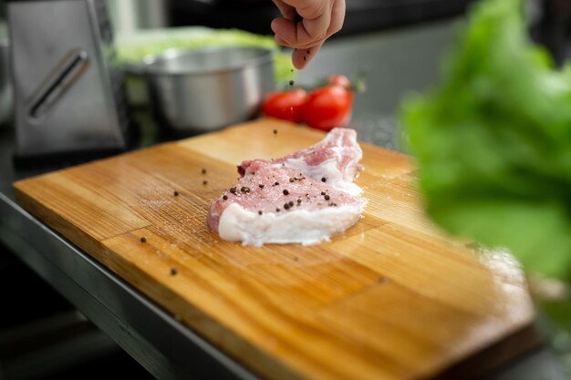 Chef piquant un steak de boeuf cru Cuisinier professionnel assaisonnant de la viande juteuse avec du sel au poivre