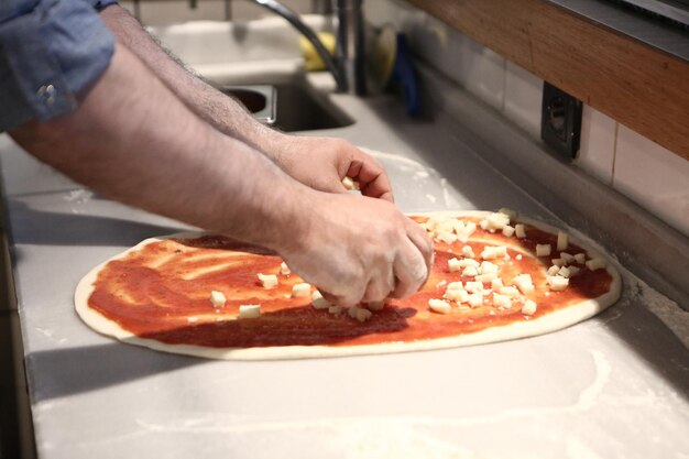 Le chef de pizza a mis la sauce sur la base dans une cuisine commerciale