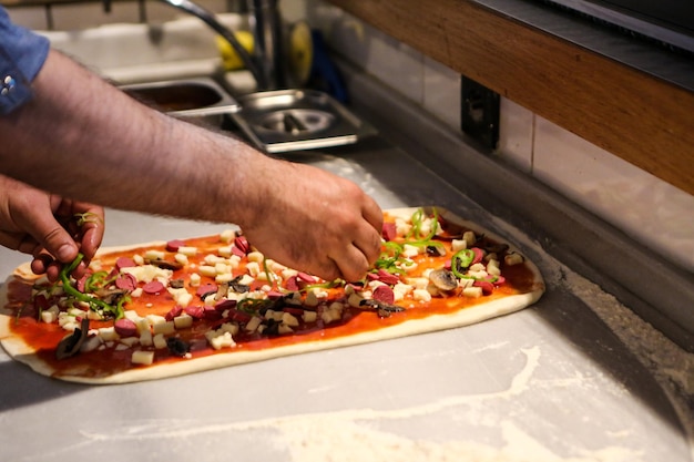 Le chef de pizza a mis la sauce sur la base dans une cuisine commerciale