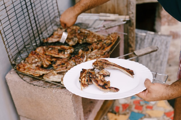 Photo le chef place les côtes d'agneau grillées sur une assiette