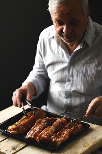 Le chef place les côtes de porc marinées sur une plaque à pâtisserie