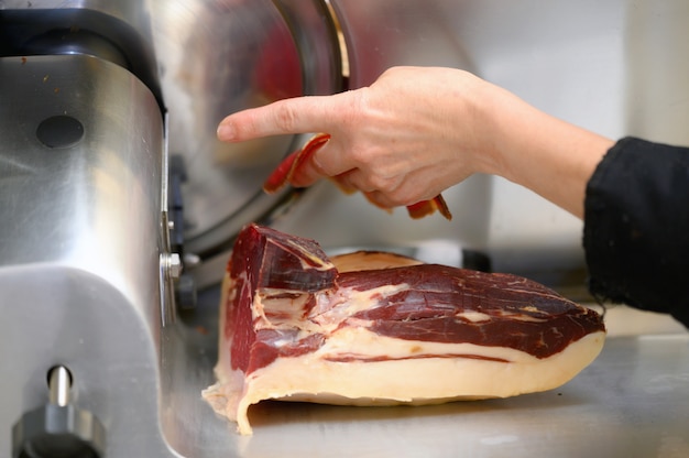 Chef portant à l'aide de la machine à trancher le jambon