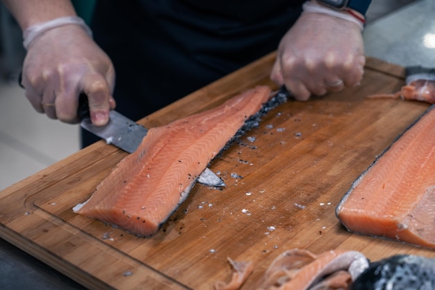 Chef préparant un poisson saumon en éviscérant et en filetant à la cuisine