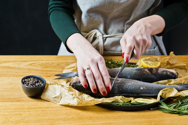 Le chef prépare le bar sur une table en bois.