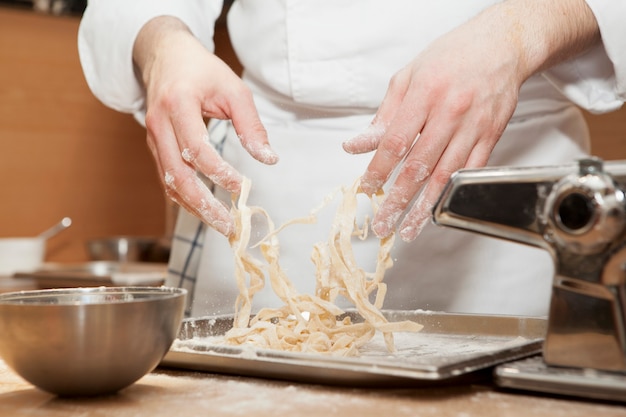 Le chef prépare des fettucines traditionnelles italiennes. Gros plan du processus de cuisson des pâtes fraîches faites maison.