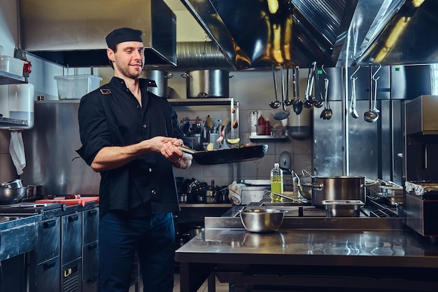 Le chef prépare des légumes secs dans une casserole dans une cuisine.