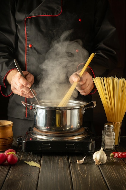 Le chef prépare des pâtes italiennes Le cuisinier garde des spaghettis dans la cuisine