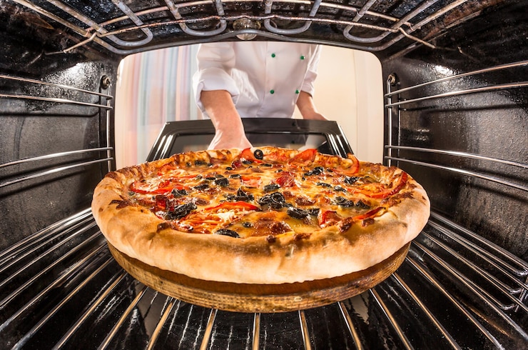 Photo le chef prépare une pizza au four, vue de l'intérieur du four. cuisson au four.