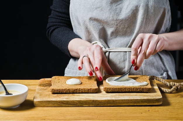 Le chef prépare un sandwich au pain noir, frotte la sauce sur du pain grillé.