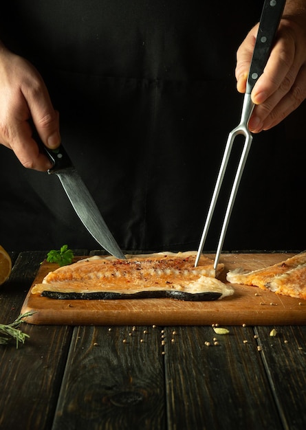 Le chef prépare un steak de truite congelé sur la table de la cuisine Le saumon est un délicieux poisson pour préparer le déjeuner ou le petit déjeuner Le processus de préparation du poisson avec des épices dans une cuisine d'hôtel