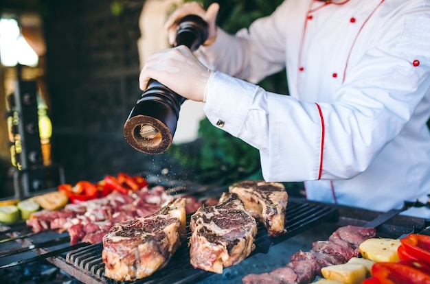 Le chef prépare la viande sur le barbecue.