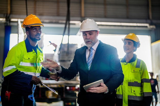 Chef principal inspectant avec des ingénieurs du personnel une femme et un homme africainL'équipe vérifie la structure de construction de l'entrepôt de l'usine avec une structure de toit en acier et l'installation de la machine