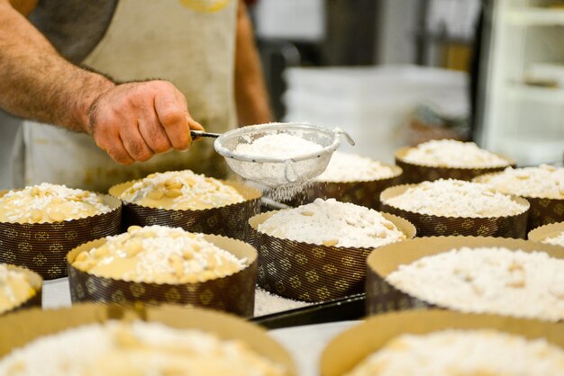 Chef produisant du panettone tout en ajoutant de la garniture de sucre d'amande au pain sucré cru