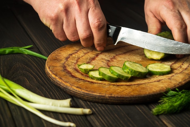 Chef professionnel coupant le concombre vert dans la cuisine