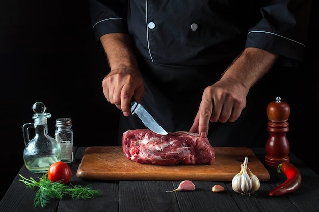 Le chef professionnel coupe la viande avec un couteau dans la cuisine prépare la nourriture