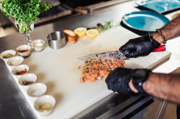 Chef professionnel dans la cuisine du restaurant préparant un délicieux repas avec de la viande et des légumes.