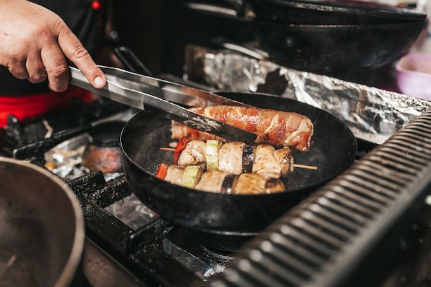 Chef professionnel dans un restaurant de cuisine préparant de la viande et des légumes.