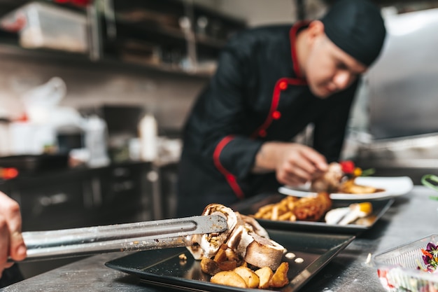 Photo chef professionnel organisant une assiette de nourriture avec de la viande et des légumes.