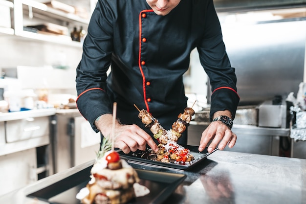 Chef professionnel organisant une assiette de nourriture avec de la viande et des légumes.