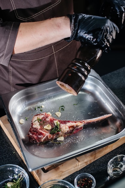 Un chef professionnel pimente un steak juteux à partir d'un morceau de viande frais. Cuisine dans un mca dans un restaurant gastronomique.