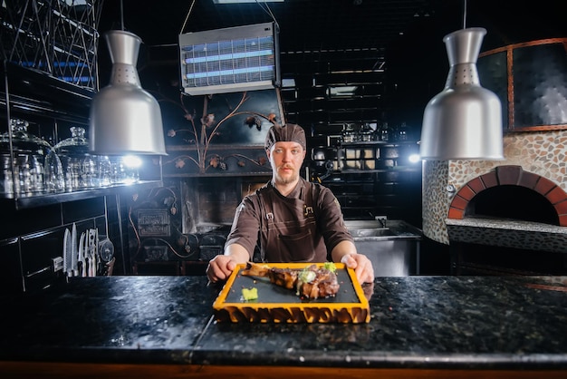 Un chef professionnel sert magnifiquement un steak grillé juteux avec du beurre et des assaisonnements. Viande grillée dans un restaurant.