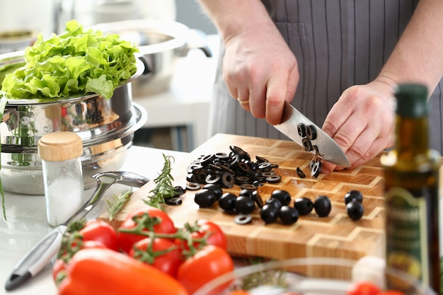 Chef professionnel tranchant l'ingrédient de la salade d'olive