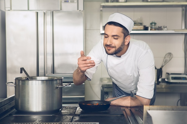 Le chef de restaurant japonais masculin faisant cuire dans la cuisine sent le plat