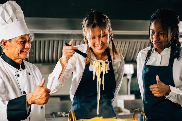 Photo le chef s'entraîne dans la cuisine les écolières cuisinent des nouilles japonaises les enfants et l'enseignant au poêle un portrait souriant de l'apprentissage est l'éducation moderne faire le dîner avec une cuillère donne de la joie concept d'éducation foor