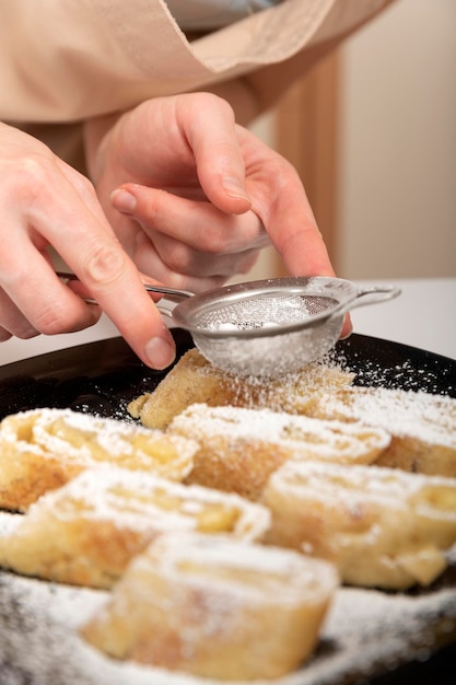 Le chef saupoudre du sucre glace sur le rouleau aux pommes Nourriture Strudel Cadre vertical